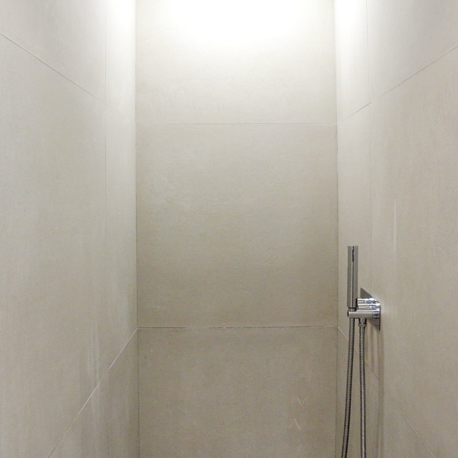 Douche avec carrelage beige et pommeau chromé