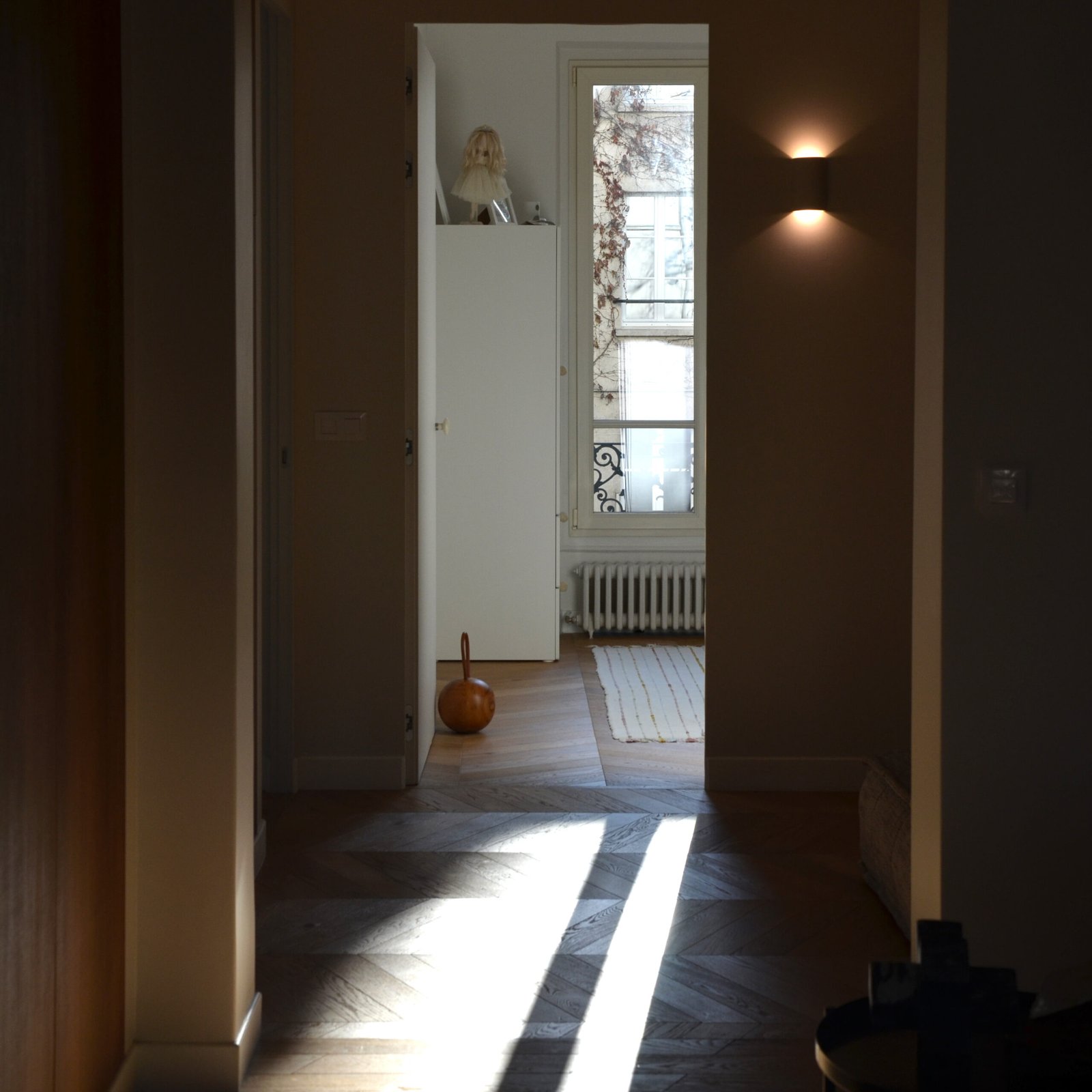 Couloir avec portes marron et vue vers chambre lumineuse